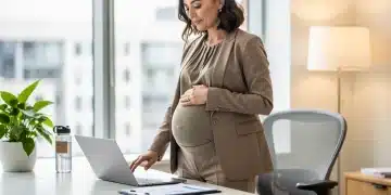 Femme enceinte professionnelle travaillant sur un ordinateur portable dans un bureau moderne, symbolisant l'équilibre maternité-carrière.