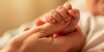 Main de bébé tenant le doigt d'un adulte, symbolisant la protection et le soin en santé infantile.