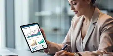 Mulher analisando gráficos financeiros em um tablet, planejando investimentos para alcançar 12% de retorno anual.