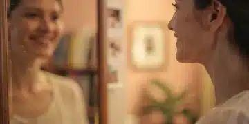 Woman smiling at a reflection, embracing her imperfections and finding peace