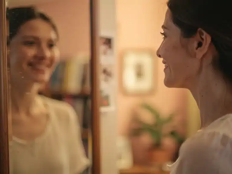 Woman smiling at a reflection, embracing her imperfections and finding peace